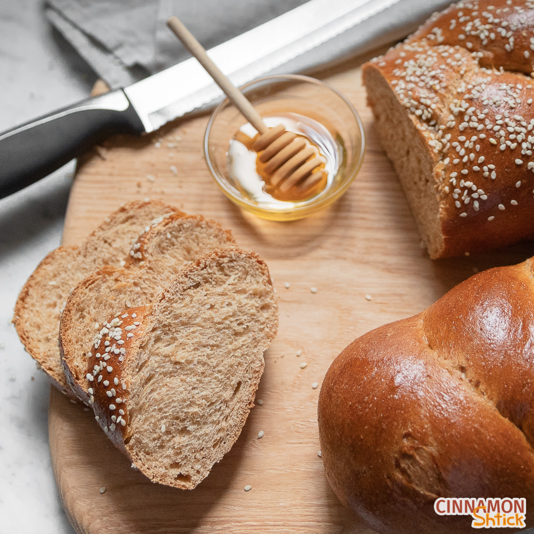 Three slices of whole wheat challah with a small bowl of honey