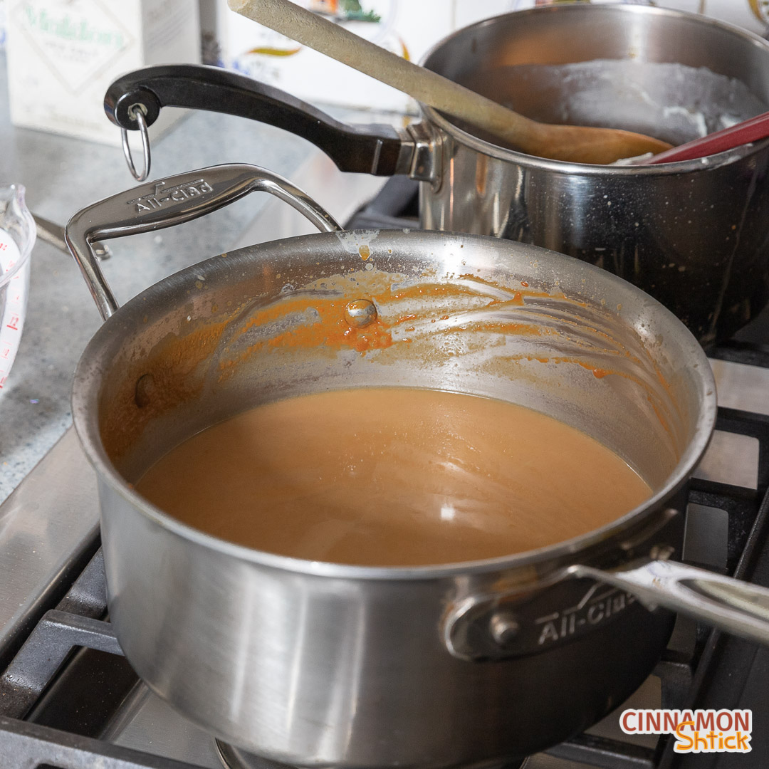 Cream and milk stirred into caramel in pot