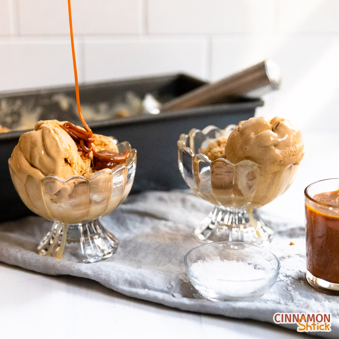 Two dishes of salted caramel ice cream with caramel sauce being poured on one of the dishes