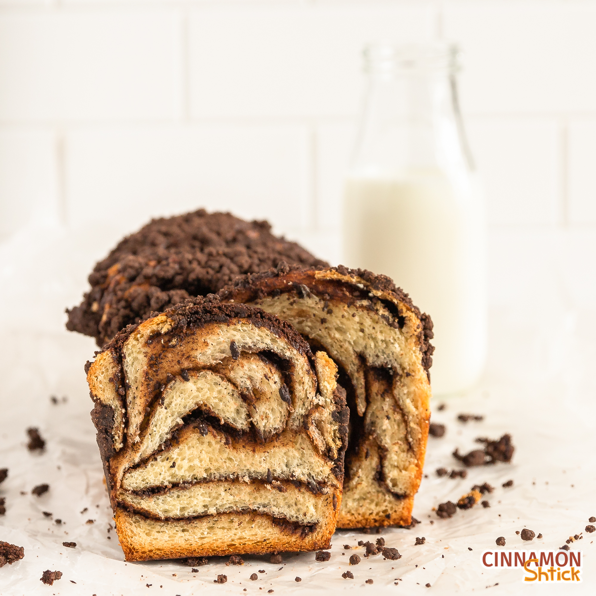 straight on shot of chocolate crumb babka showing the chocolate swirls in the babka with a bottle of milk in background