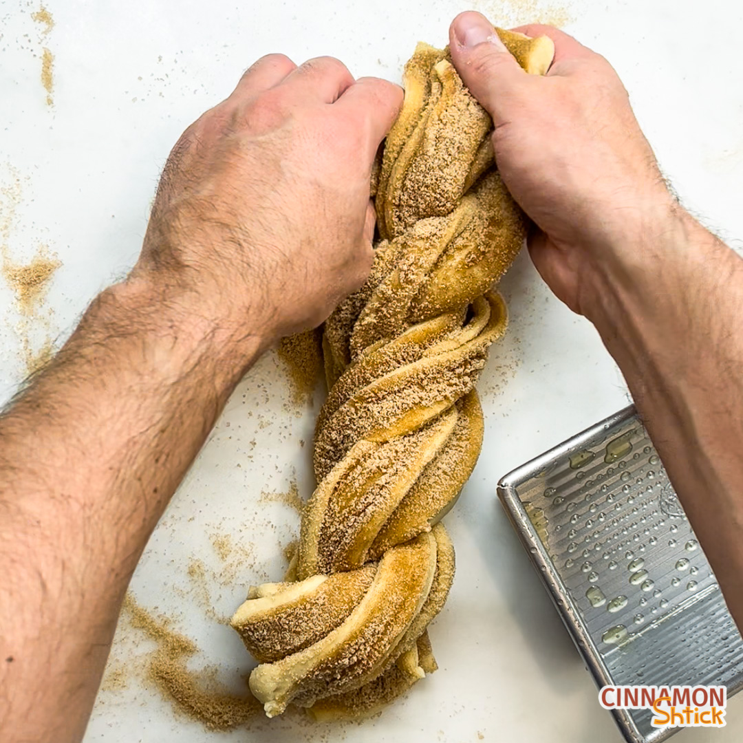 overhead view showing hands twisting the babka just before placing it into prepared pan