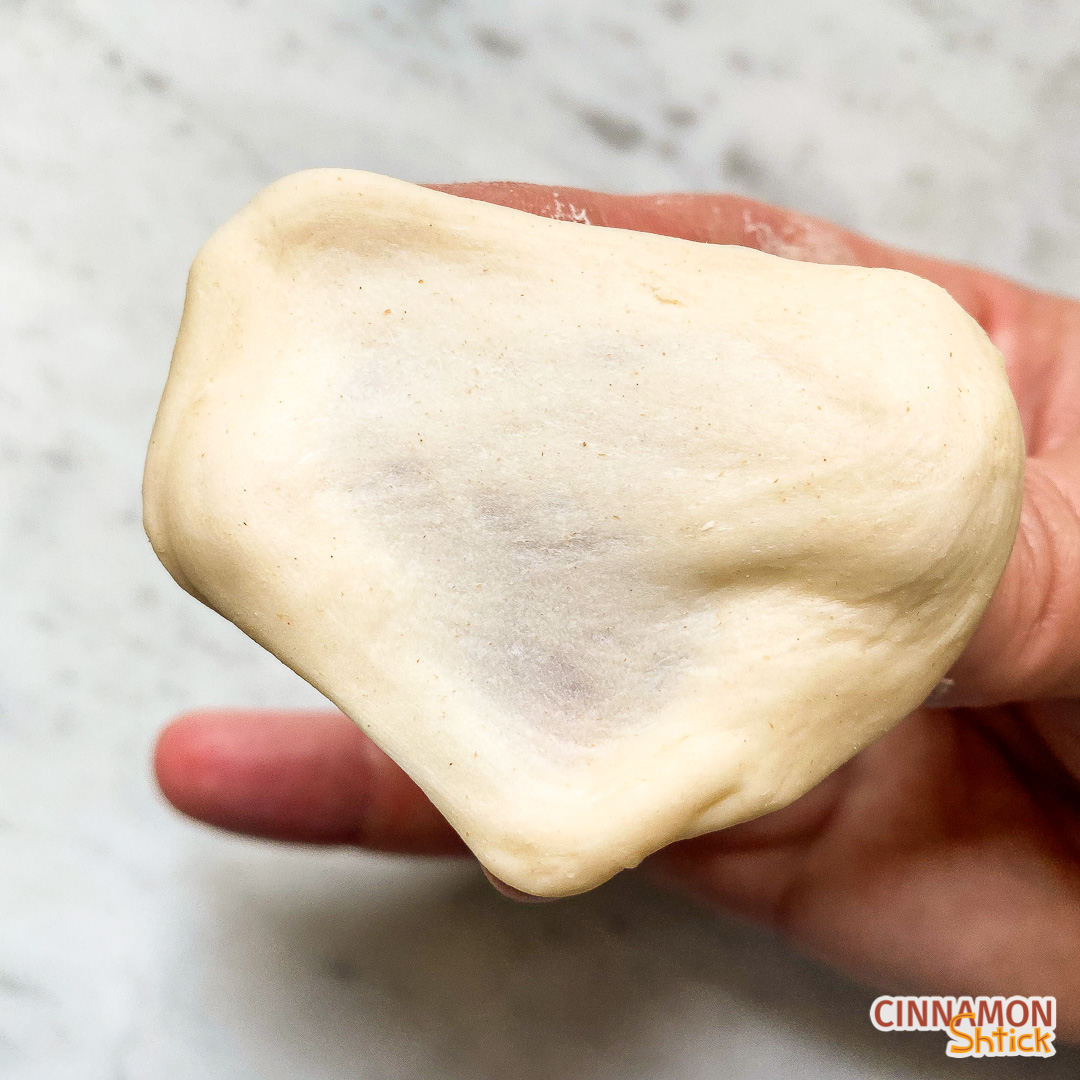 Piece of dough spread thin to show that it is translucent without ripping and therefore passing the windowpane test