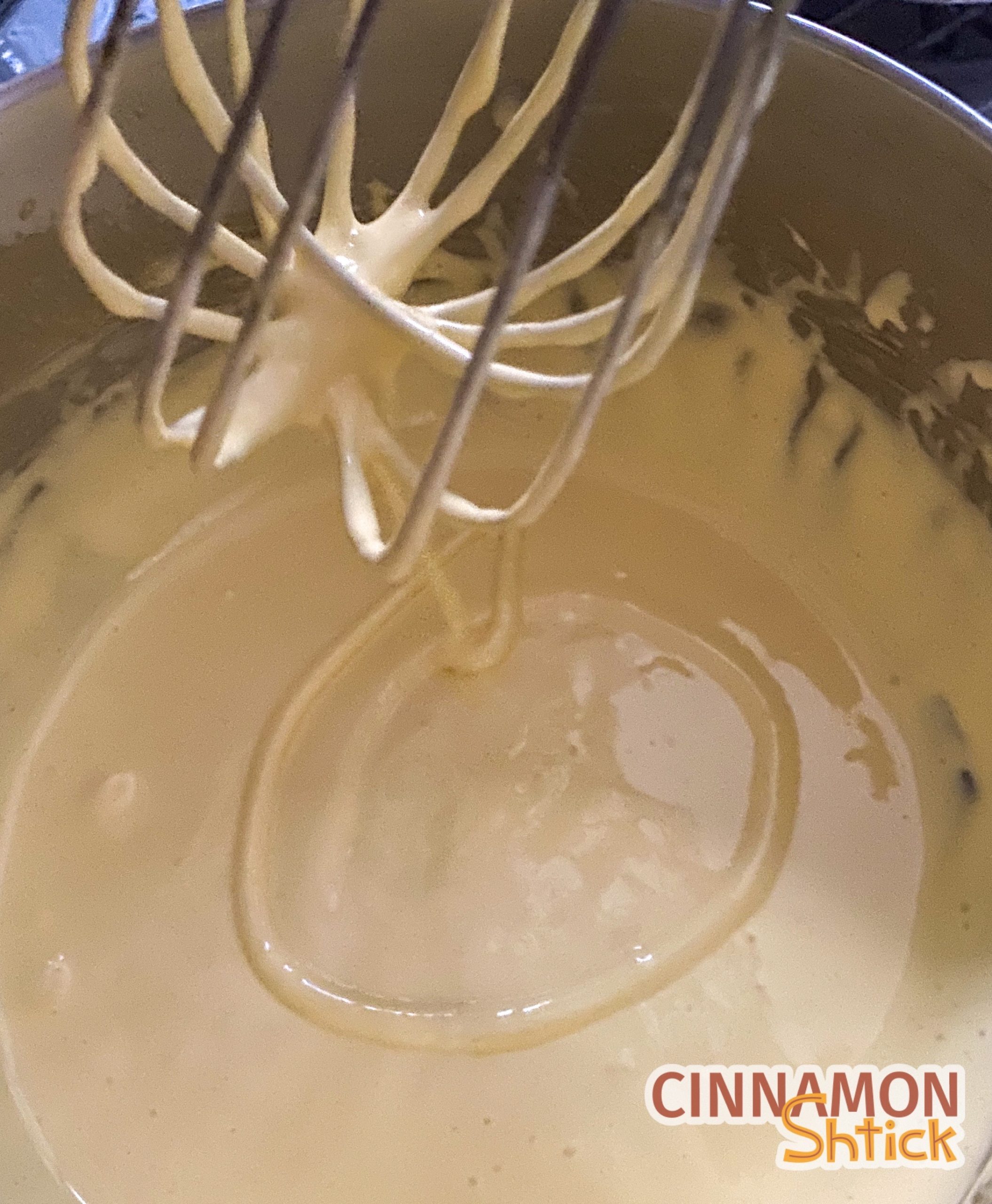 yoks and sugar whisked in bowl with whisk above showing ribbon of mixture in bowl