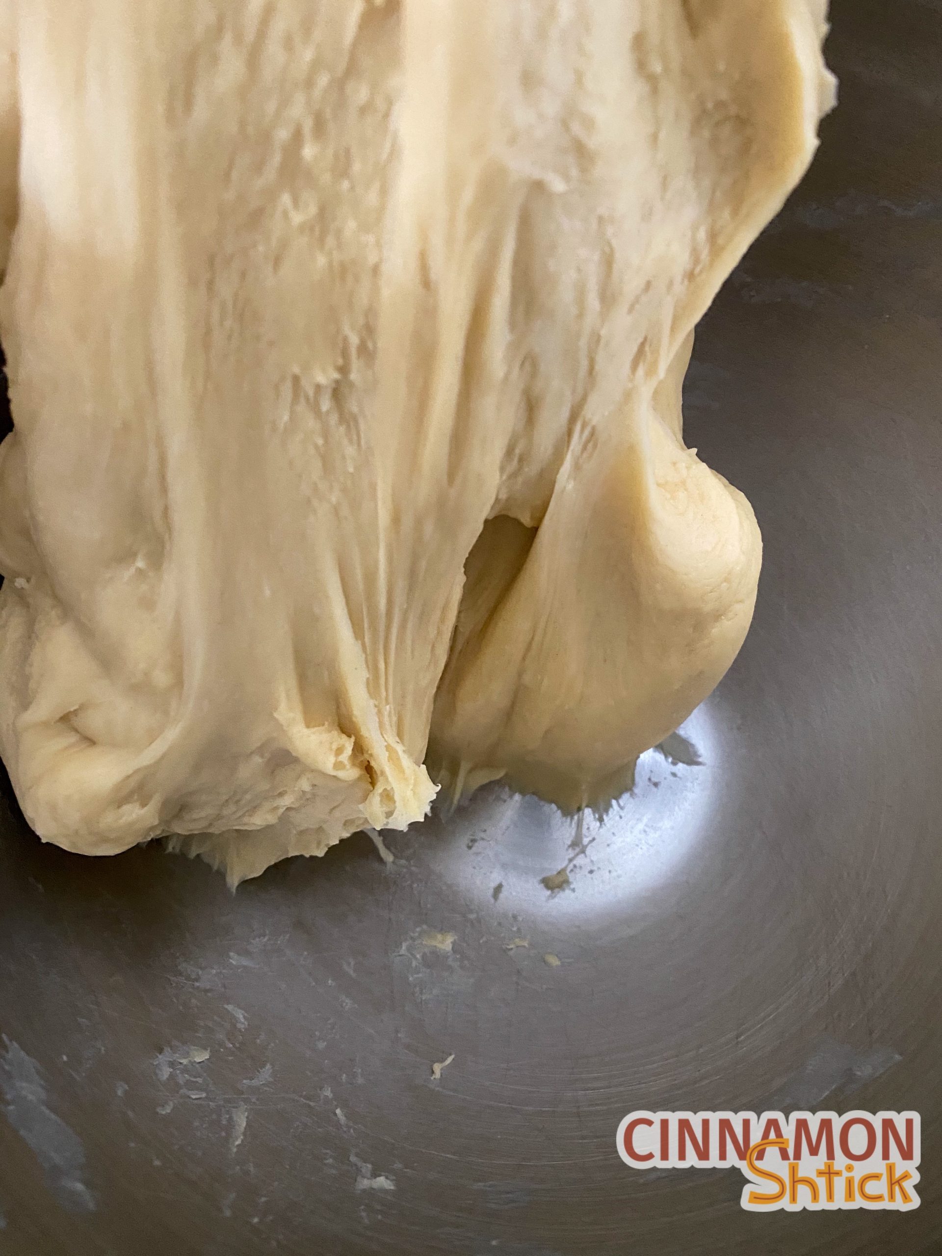 Dough after kneading, being lifted from the mixer bowl.