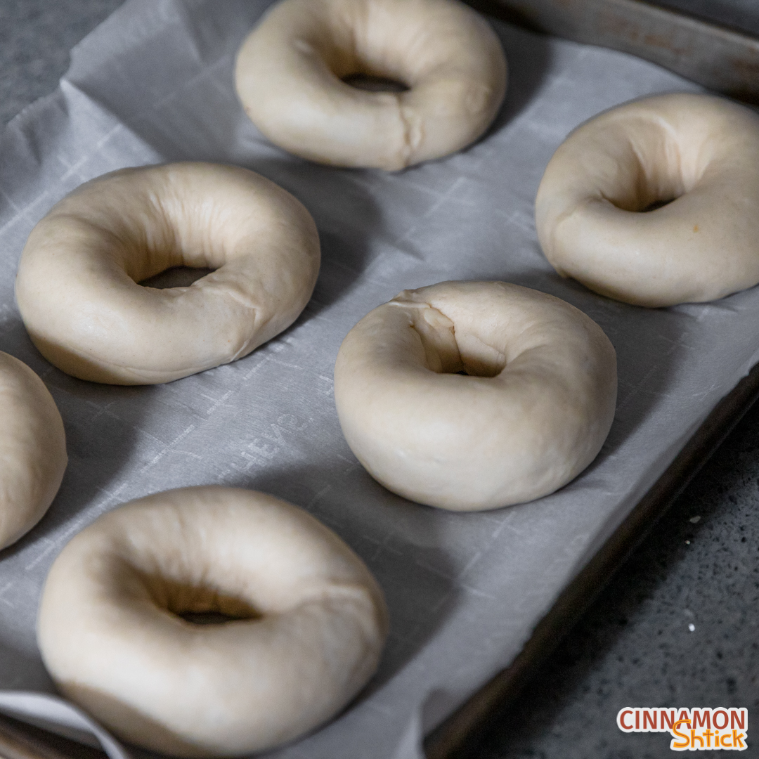 six shaped bagels ready to be boiled and baked