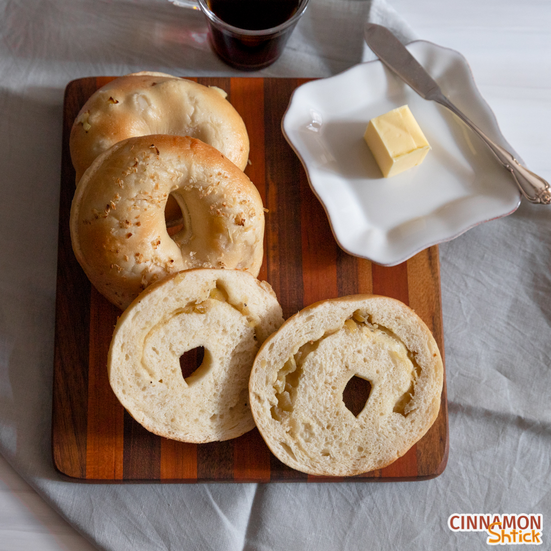 Onion stuffed bagel sliced in half with pat of butter on plate