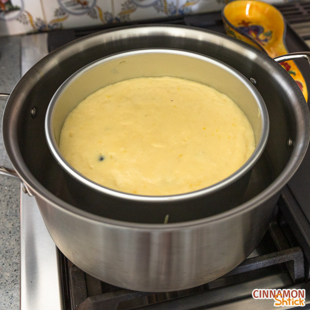Cake batter sitting in pan on top of foil ring in large pot