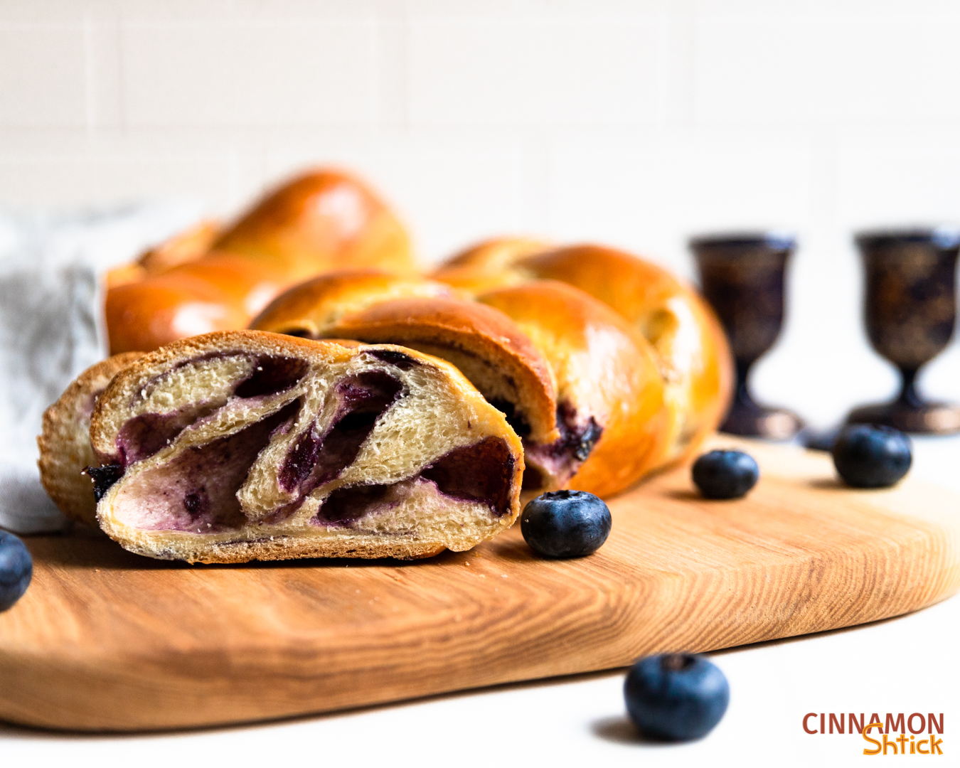 Slice of blueberry babkallah with candlesticks in background