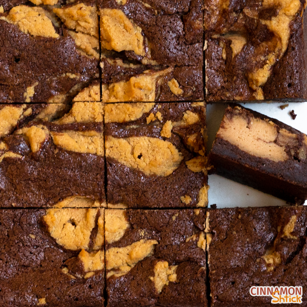 Square of Peanut Butter Cheesecake Brownies cut into 9 pieces with the brownie in the right column middle row, facing upward to see the inside of the brownie