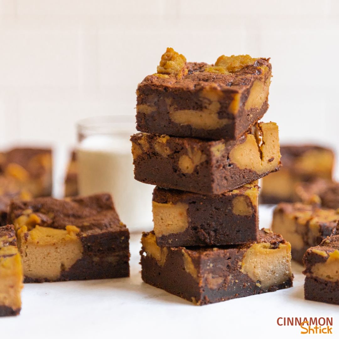 Stack of peanut butter cheesecake brownies with glass of milk in background