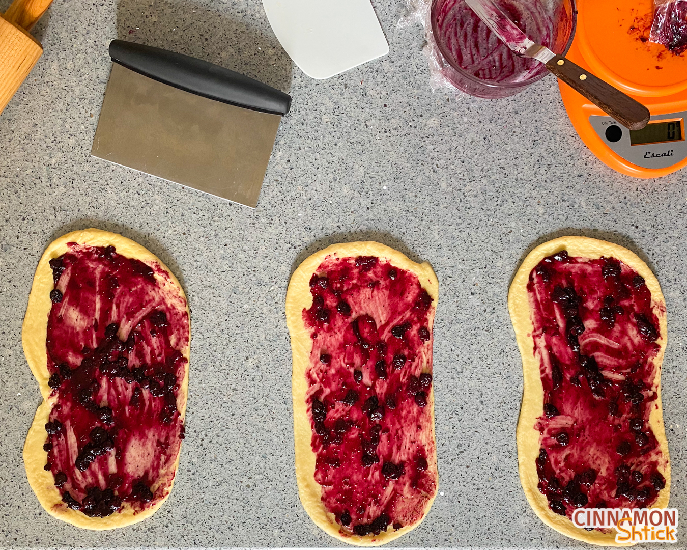 Three strands of challah dough rolled out to rectangles with blueberry filling spread on each.