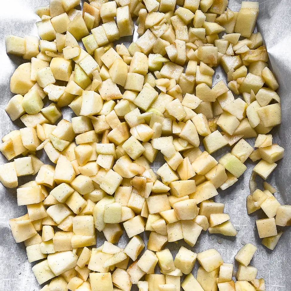 Chopped apples spread in a single layer on a baking sheet ready to be roasted