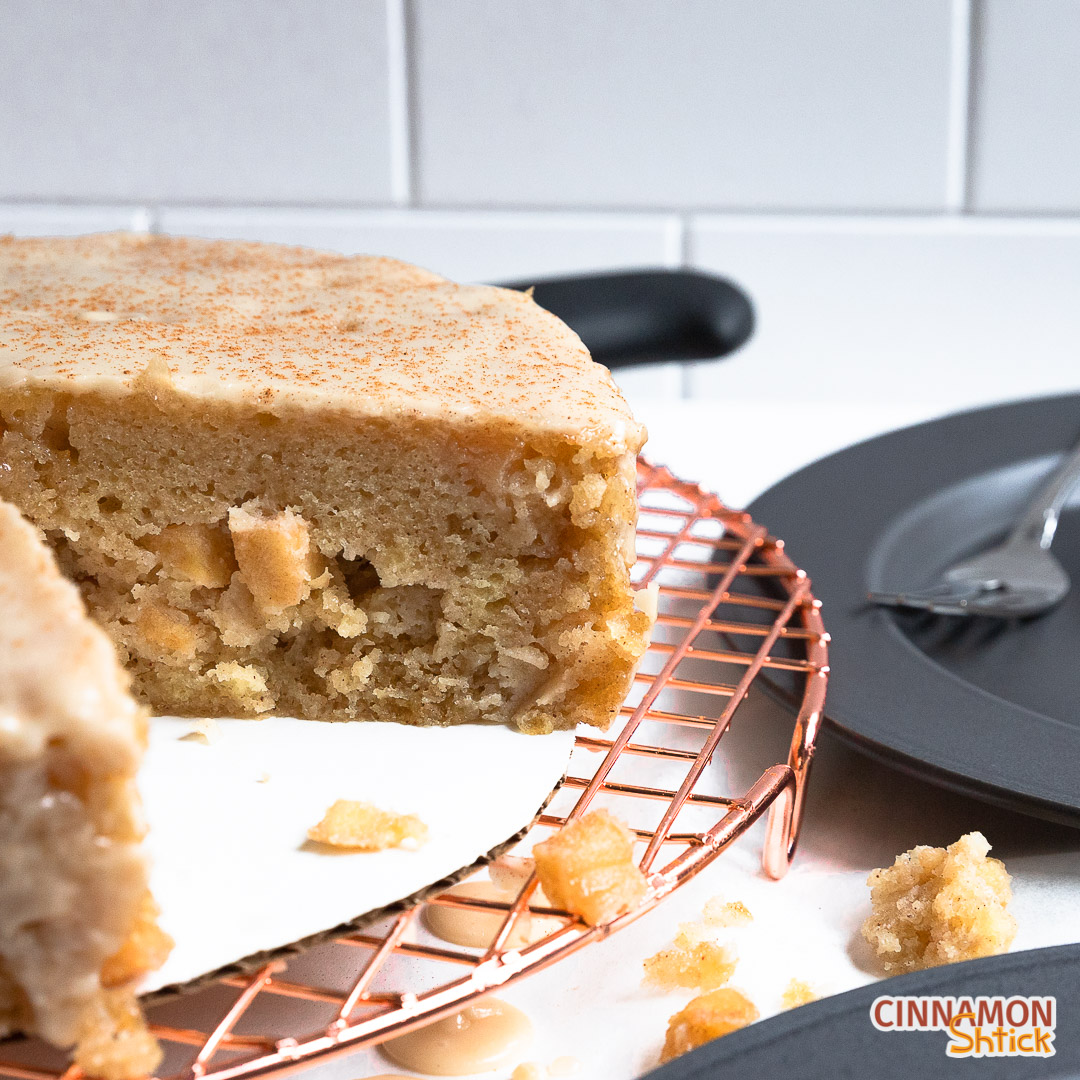 Apple Cinnamon Stovetop Cake with a few slices missing, sitting on cooling rack with a couple of plates in the background