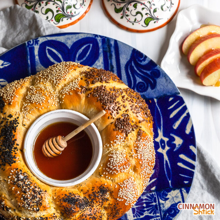 Three strand challah formed in a circle with a bowl of honey in the center.