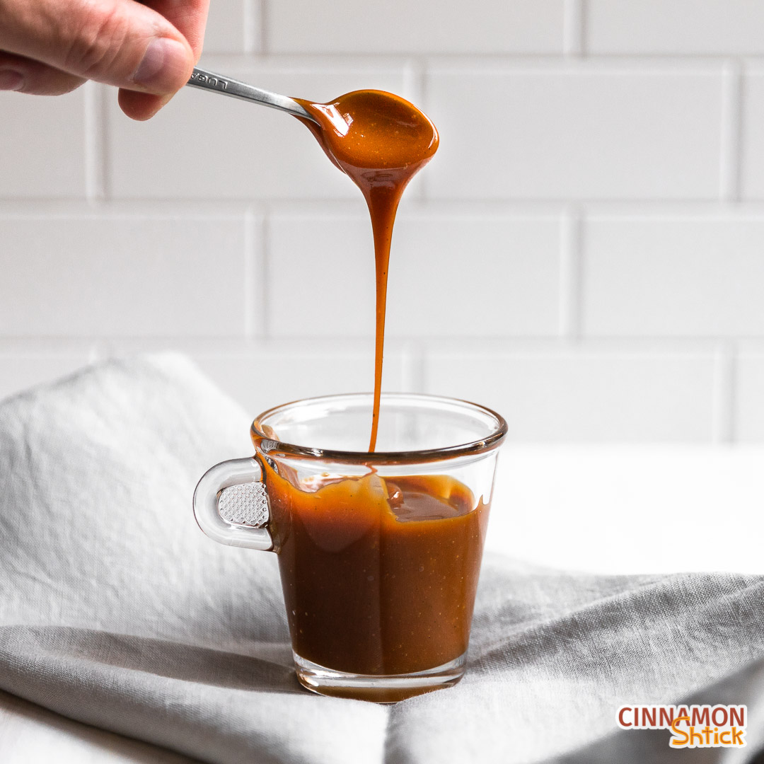 Caramel sauce falling from a spoon into a small cup