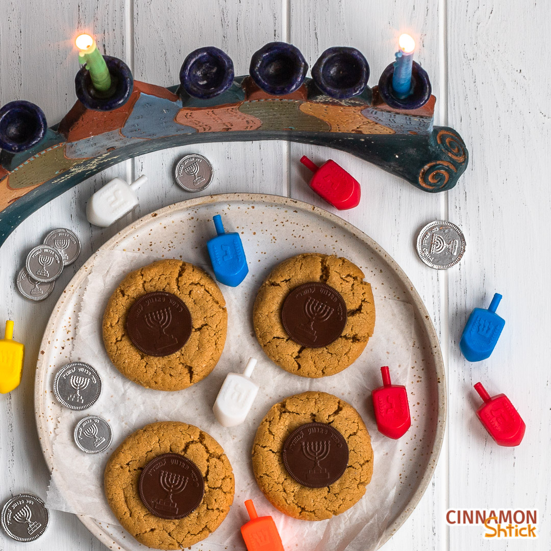 Plate of 4 peanut butter gelt Hanukkah cookies in front of menorah