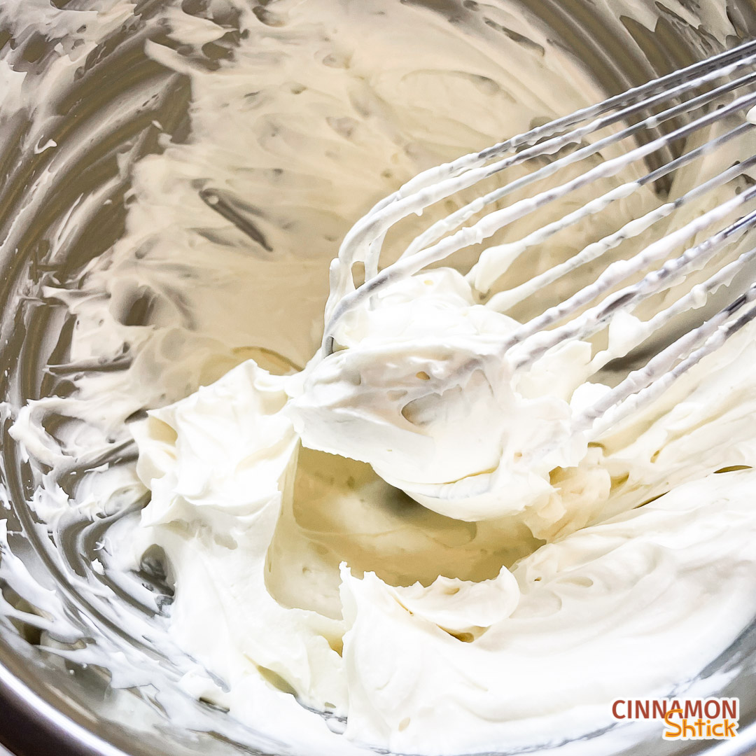 whipped white chocolate ganache in bowl with whisk