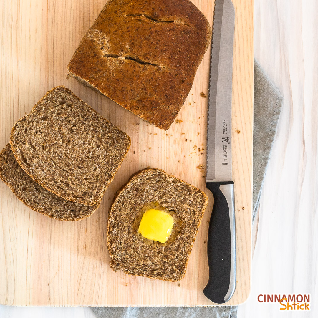 sourdough discard sandwich bread on cutting rack with knife, two stacked slices and one slice with butter melting in the middle