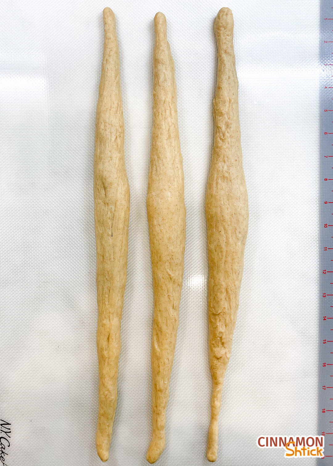 Three strands of sourdough challah dough, showing that the ends are tapered.