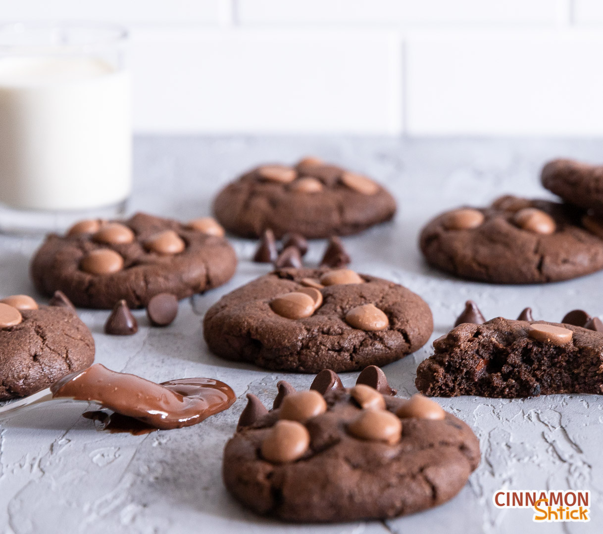 chocolate chocolate chip cookies on counter with glass of milk in background