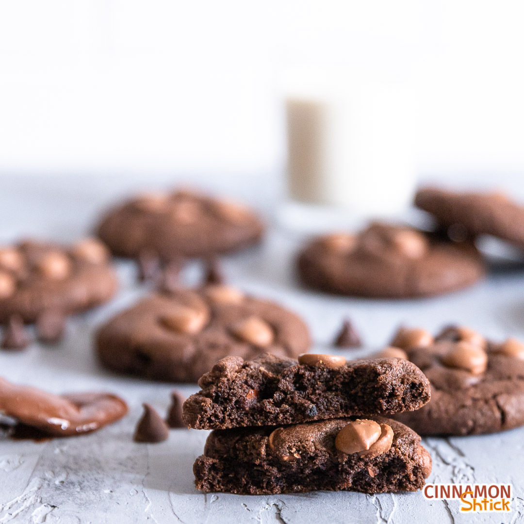 chocolate chocolate chip cookie broken in half in forefront with full cookies in background