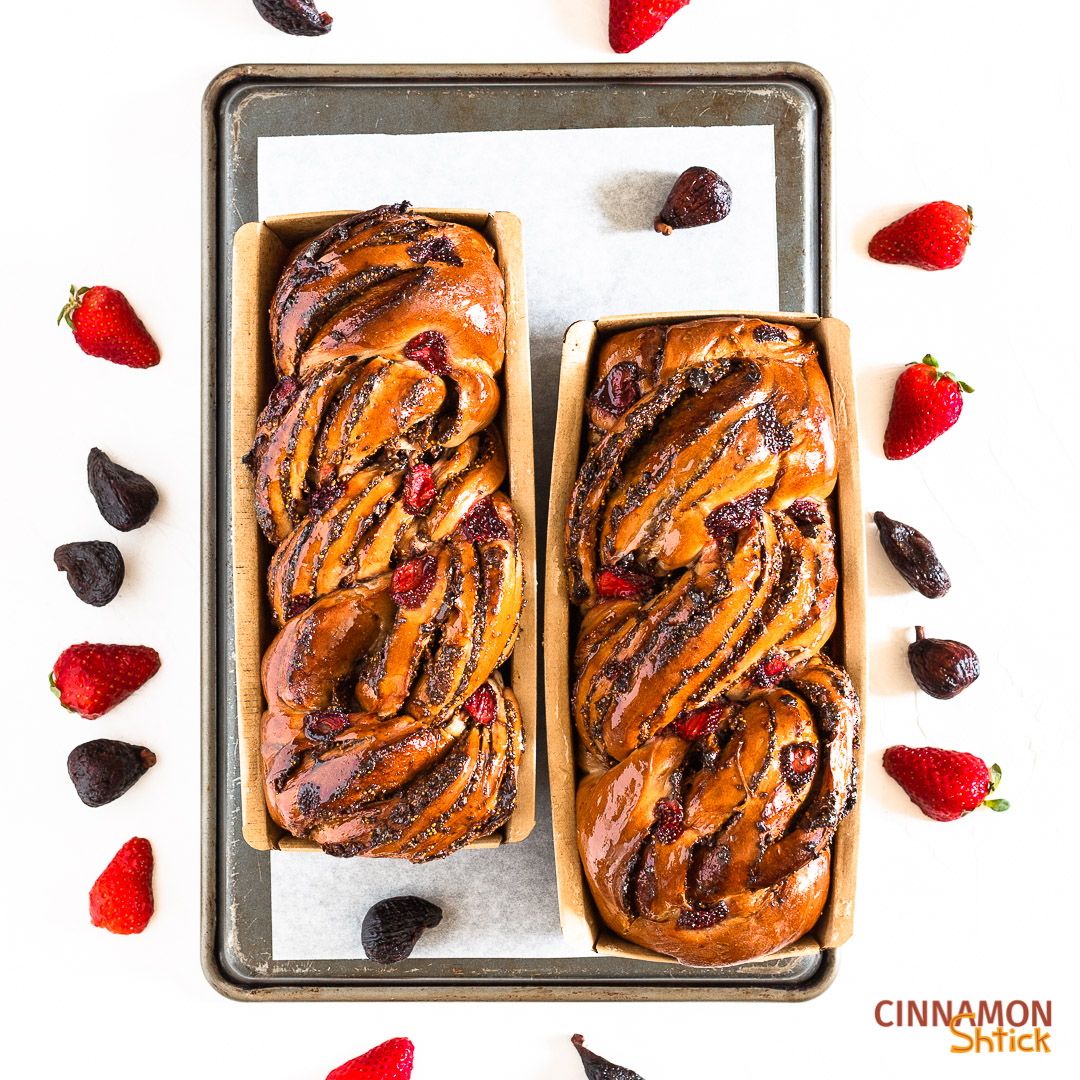 Two loaves of strawberry fig babka with figs and strawberries surrounding them