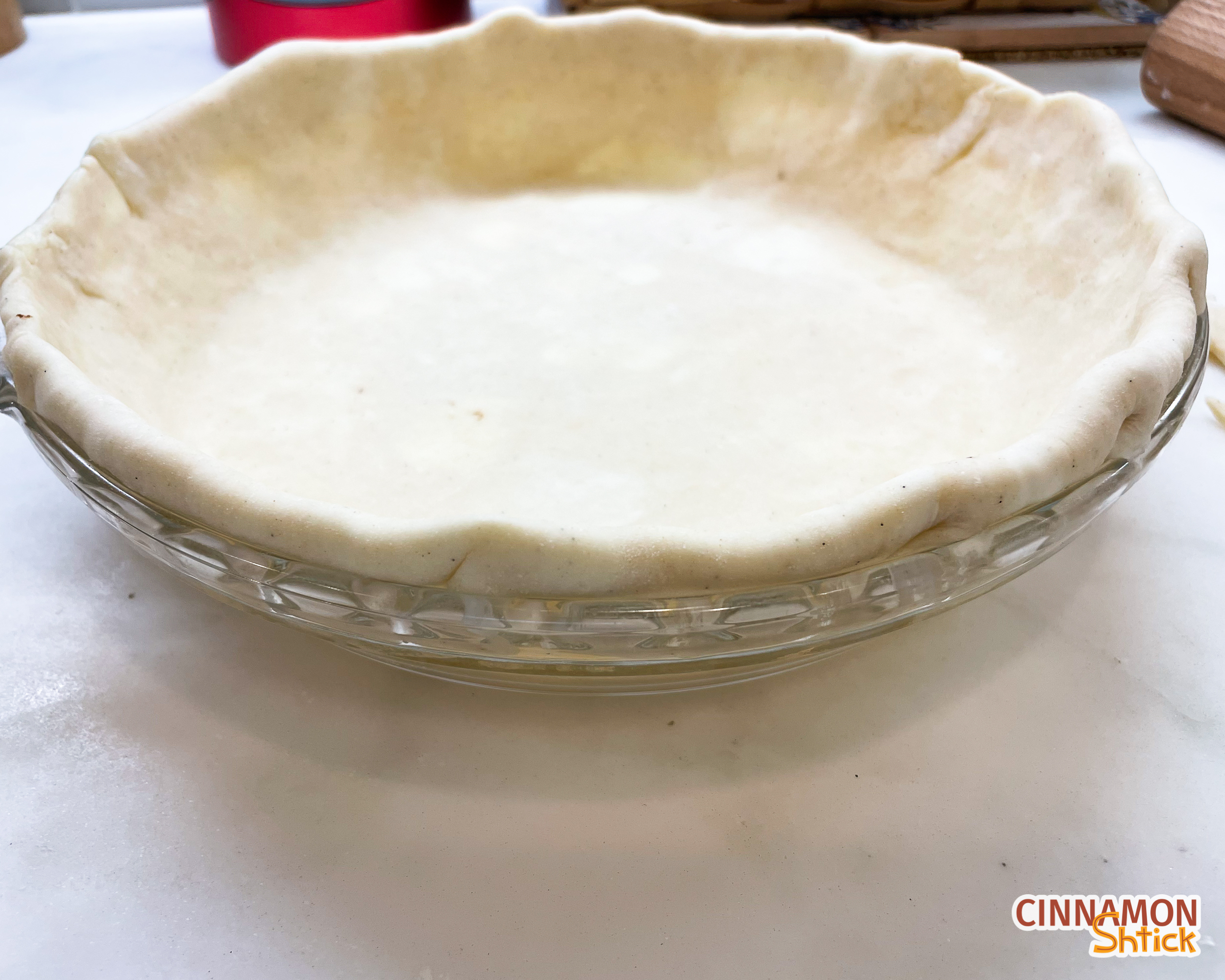 side view of pie dough in pie plate showing that the overhand was tucked into the pie dish