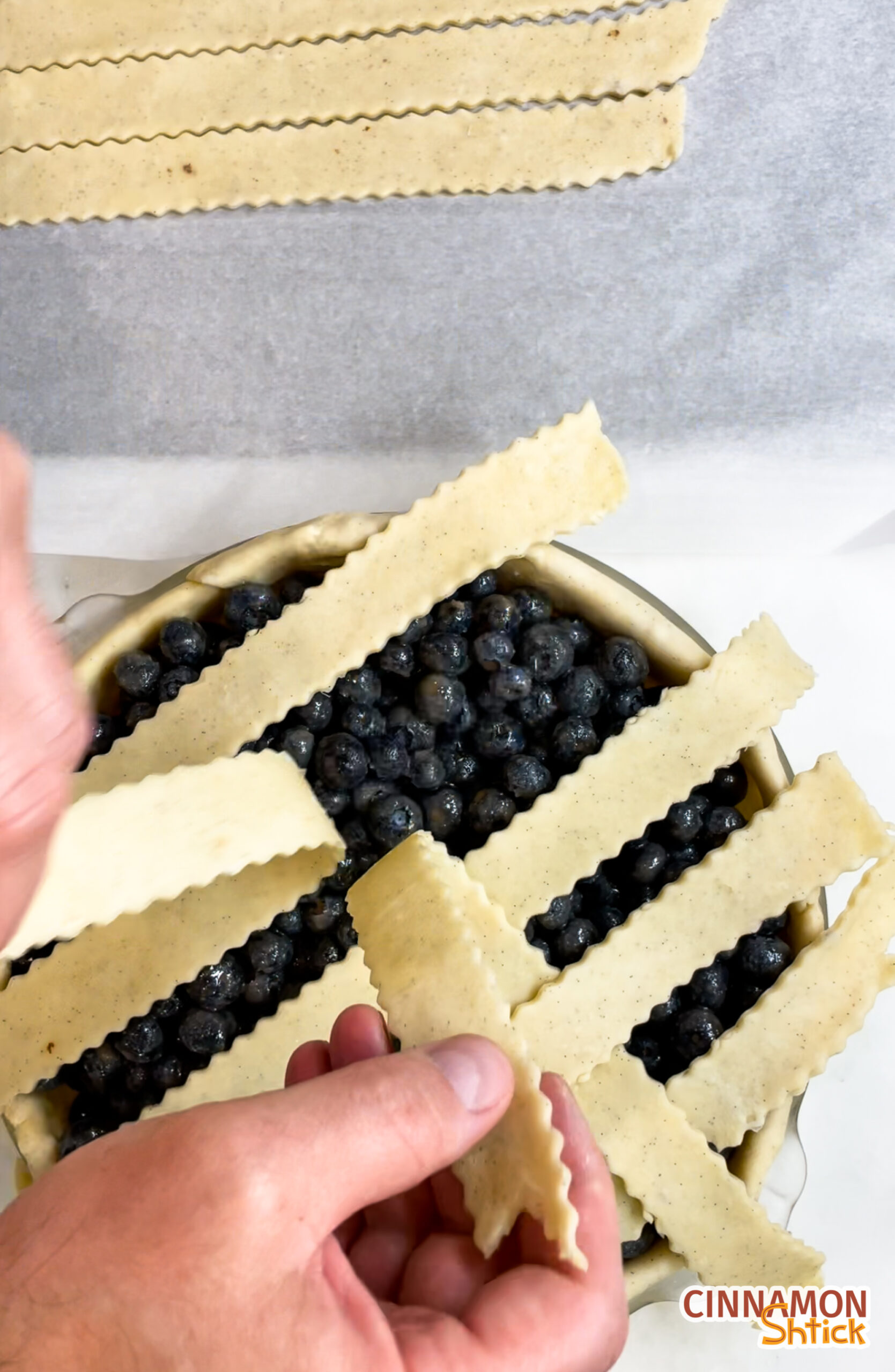 overhead view of the middle of placing cross-strips of pie dough to form a lattice