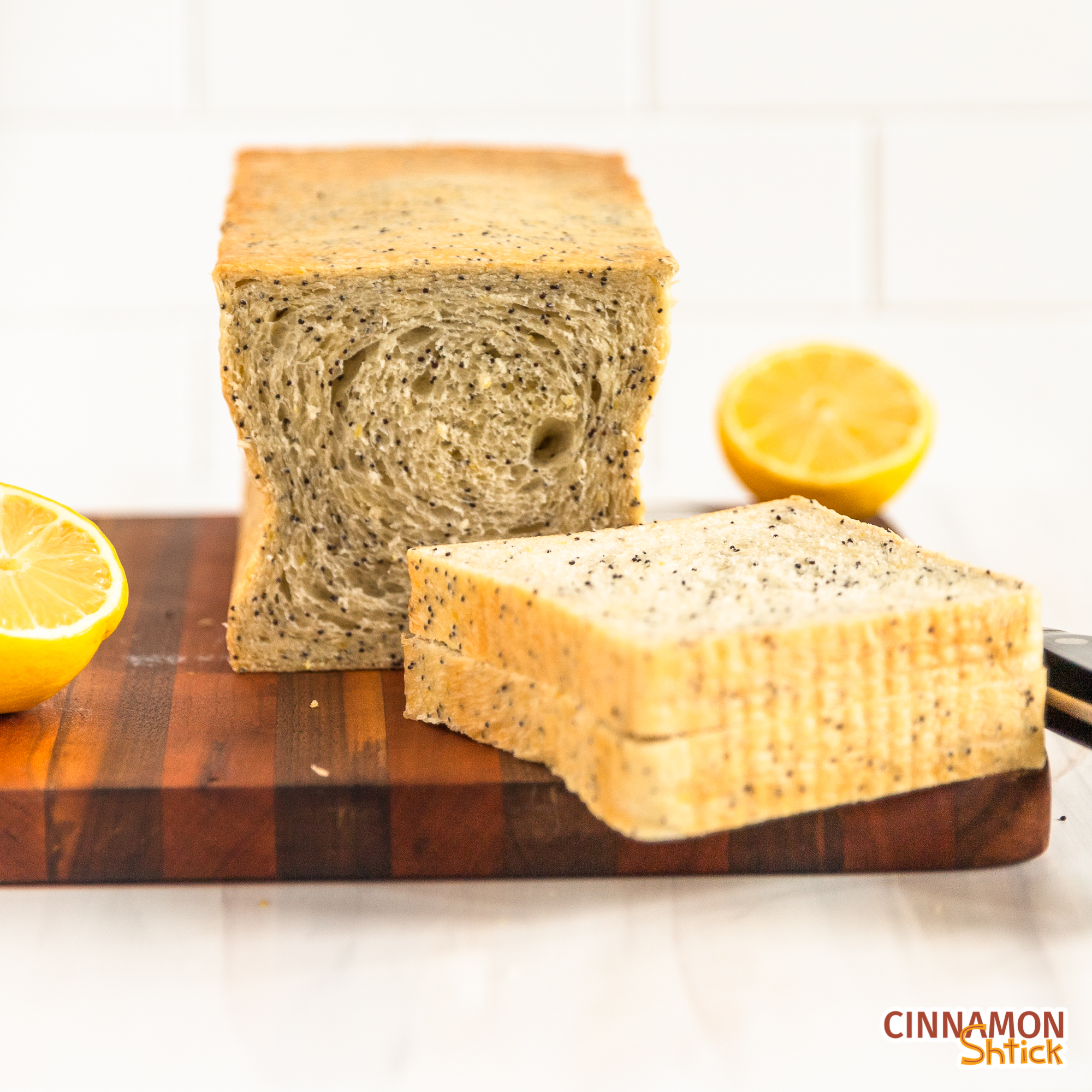 lemon poppyseed sourdough bread on a cutting board with two slices in the forefront