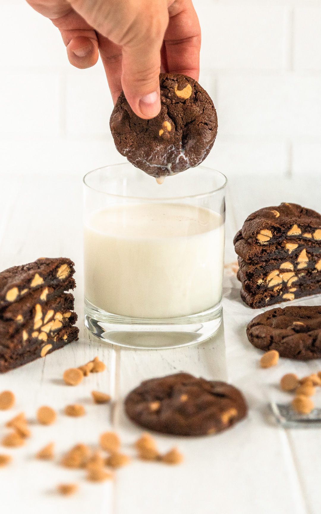 hand dipped a chocolate peanut butter chip cookie in a glass of milk