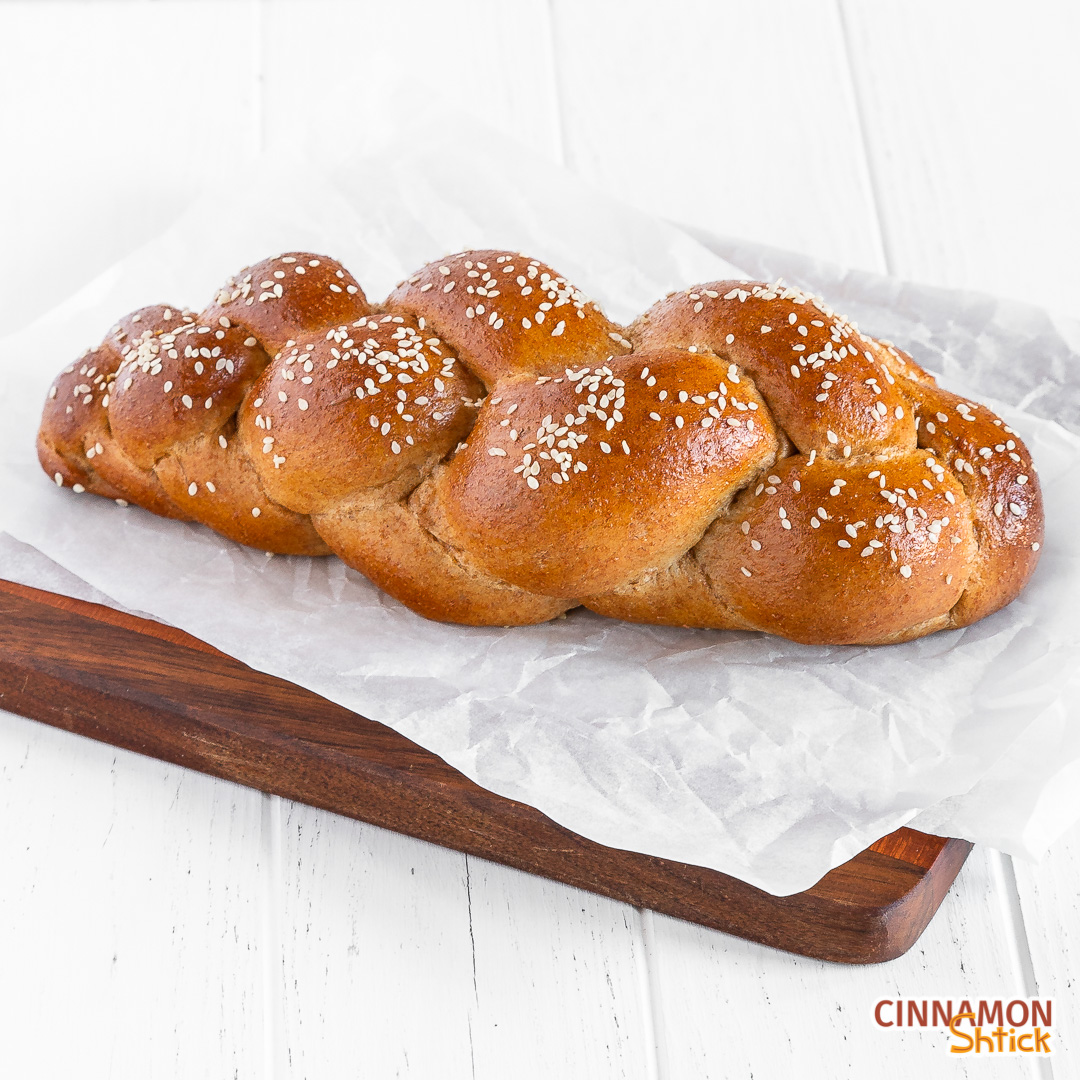 45 degree angle view of braided spelt challah on parchment paper on a cutting board