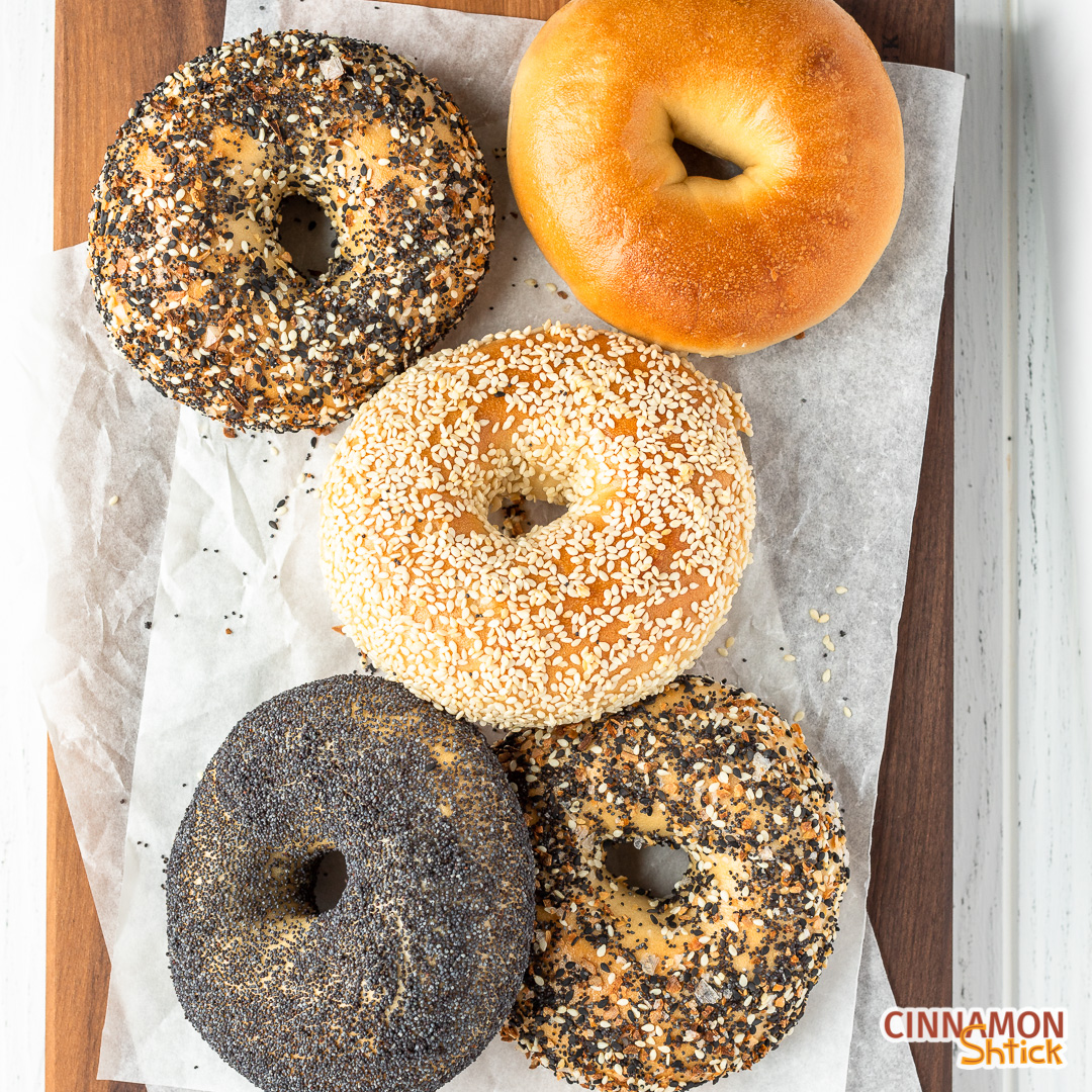 overhead view of 5 New York Bagels, poppyseed on bottom left, everything on bottom right, sesame in middle, everything in upper left and plain in upper right