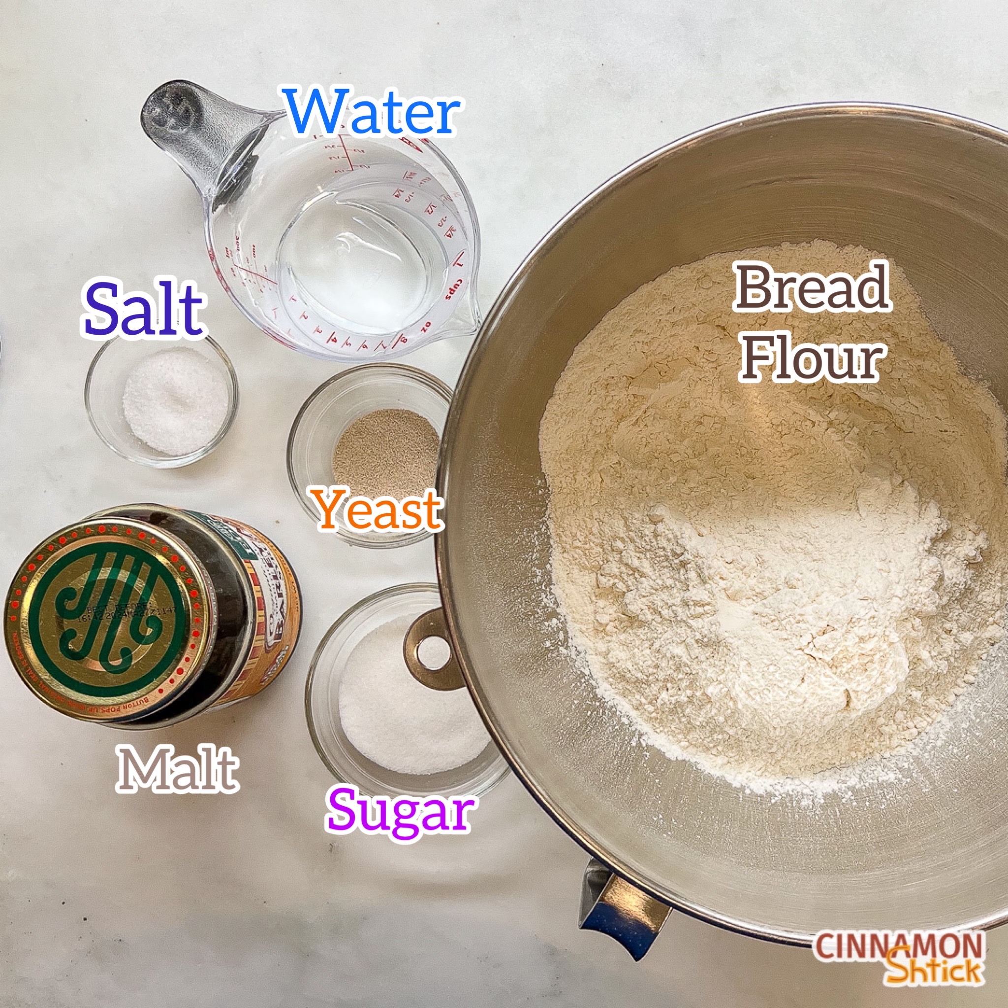 overhead view of all ingredients for bagels: bread flour, water, salt, yeast, sugar, and malt