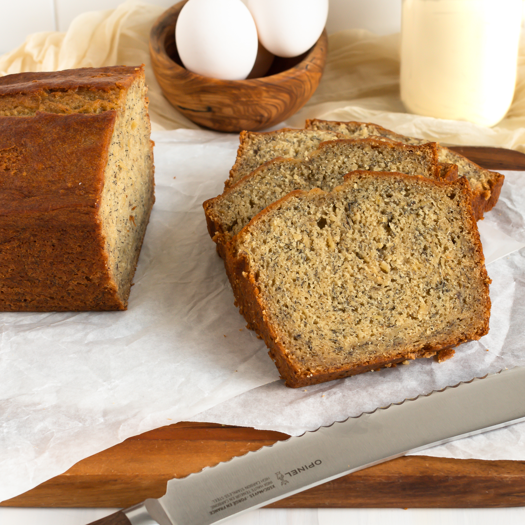 a few slices of banana bread on a cutting board with the rest of the loaf and a bread knife