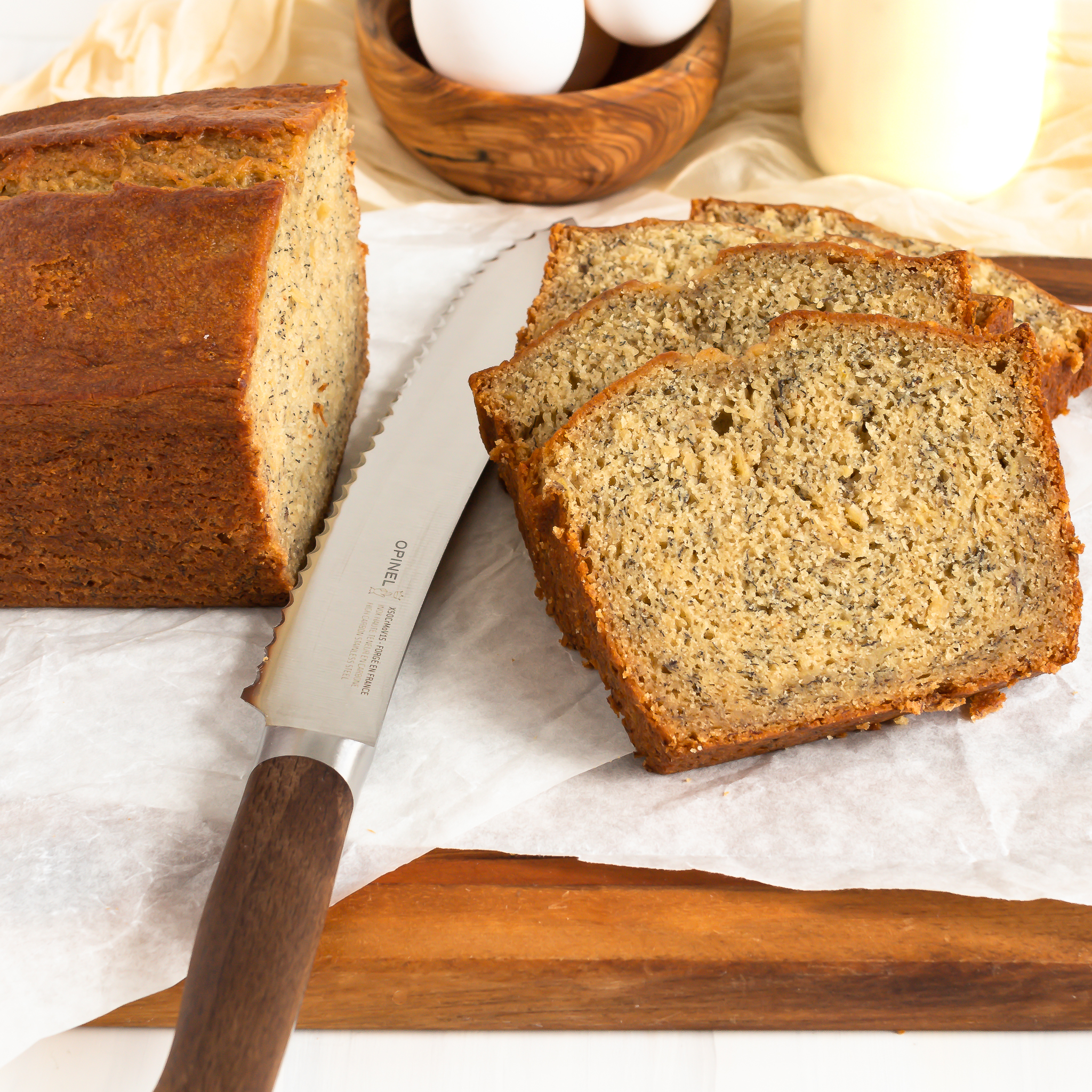 a few slices of banana bread on a cutting board with the rest of the loaf and a bread knife