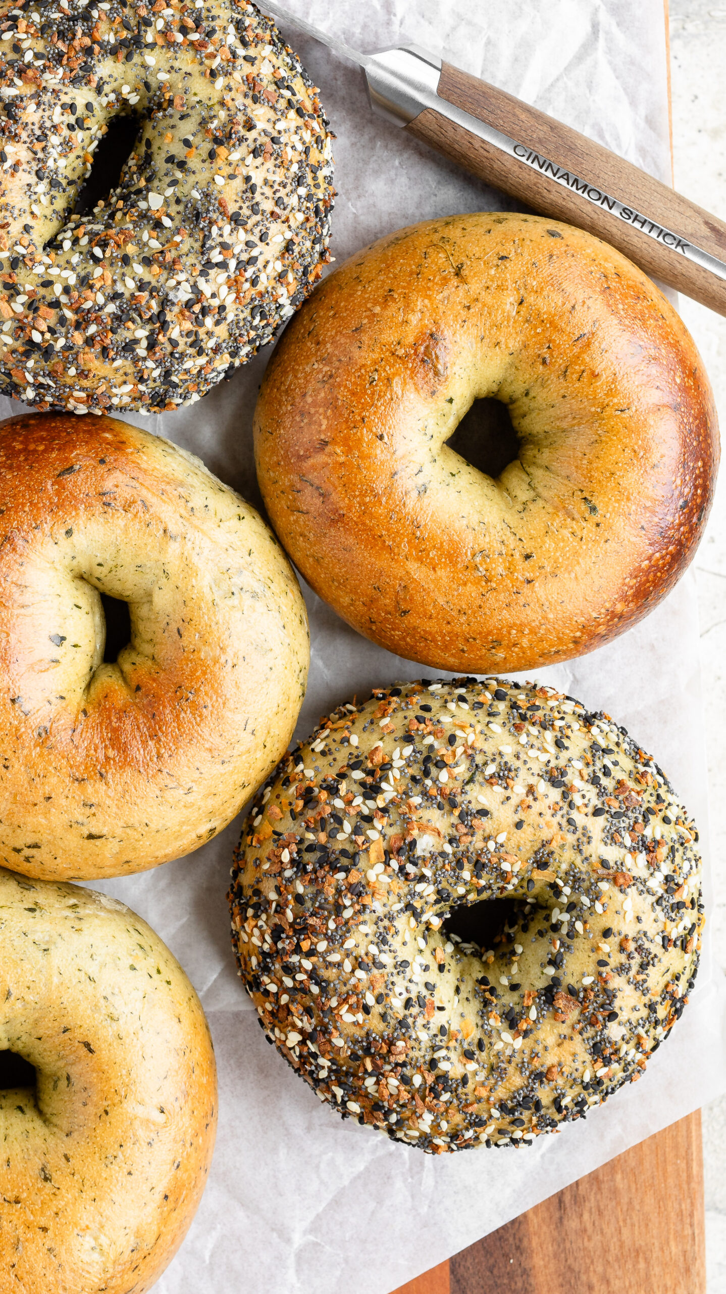 Overhead of 5 spinach bagels, two with everything seasoning all over them.