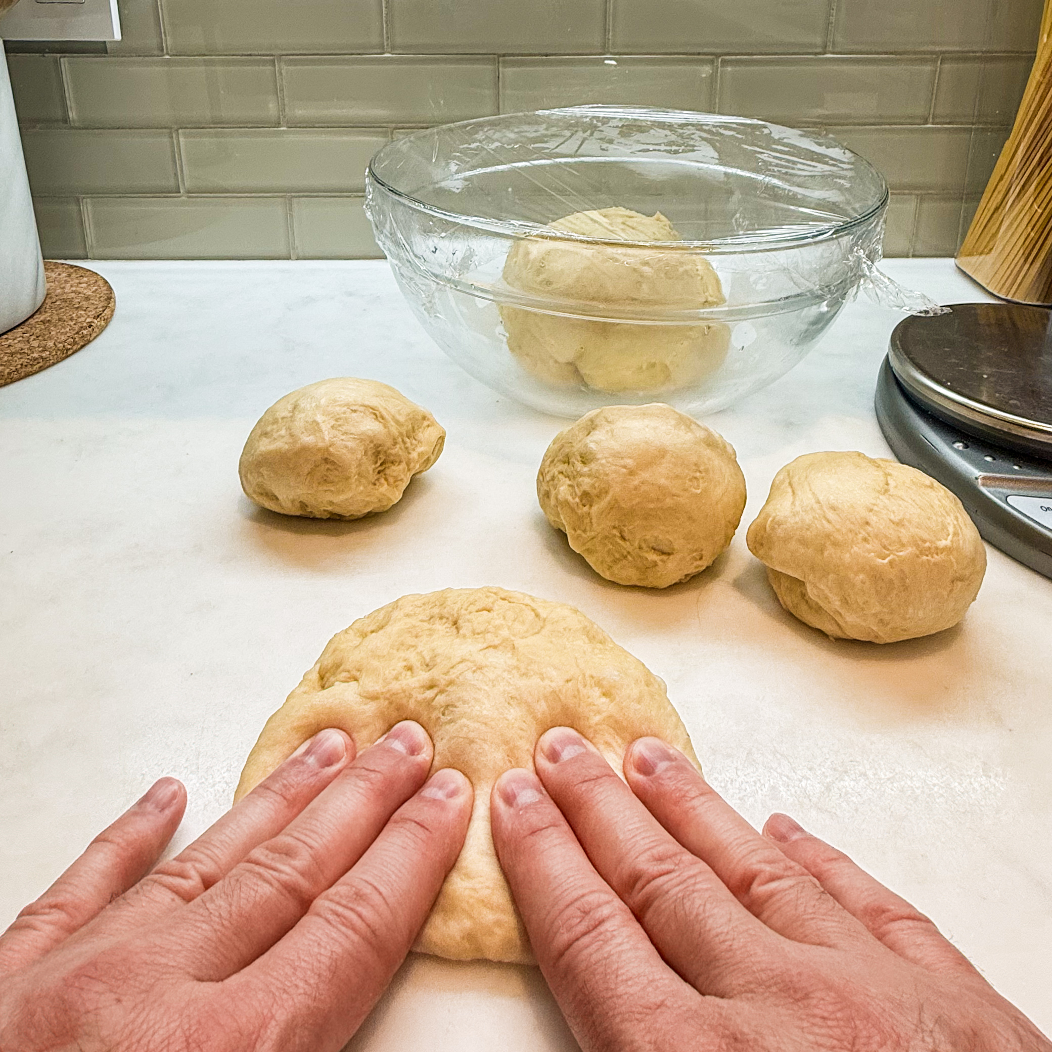 Pressing down ball of dough into an oval shape with fingertips.