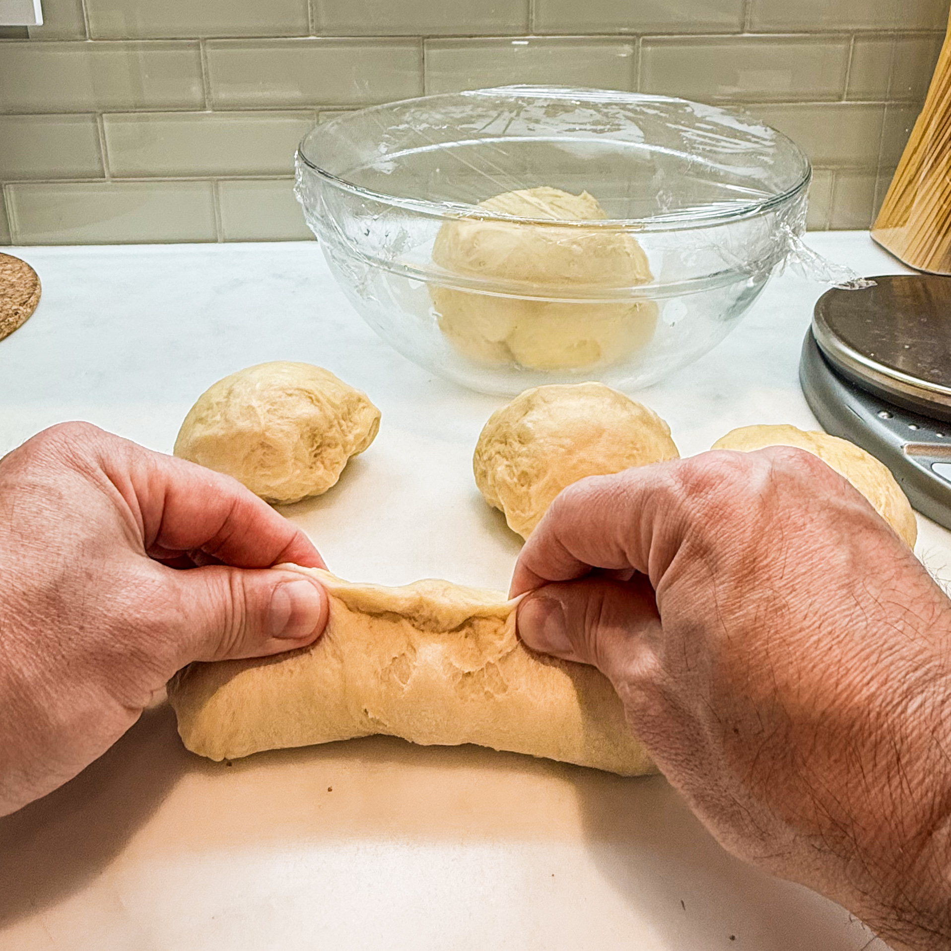 Two hands pinch the seam of a rolled up portion of dough.