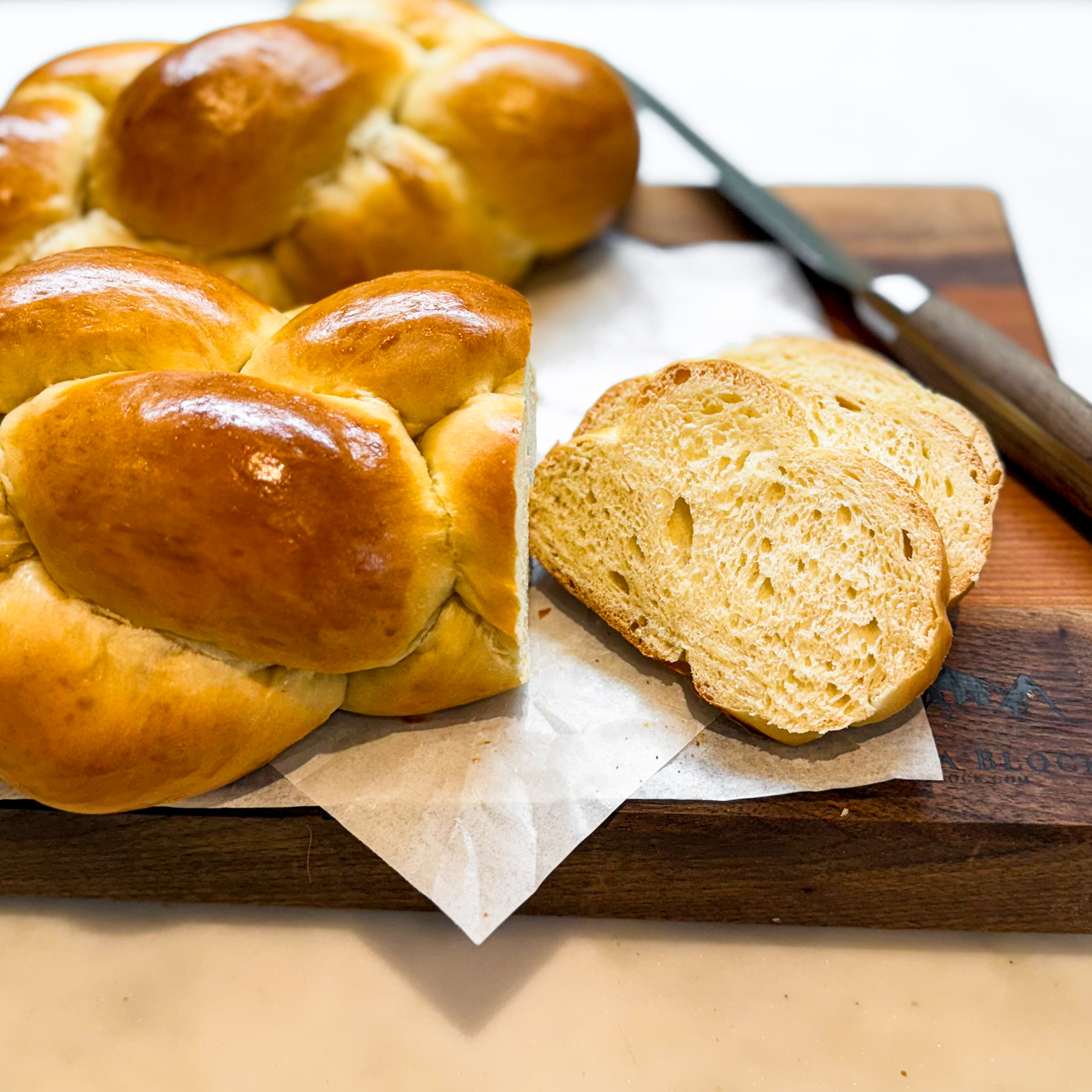 Challah with a few slices on a cutting board.