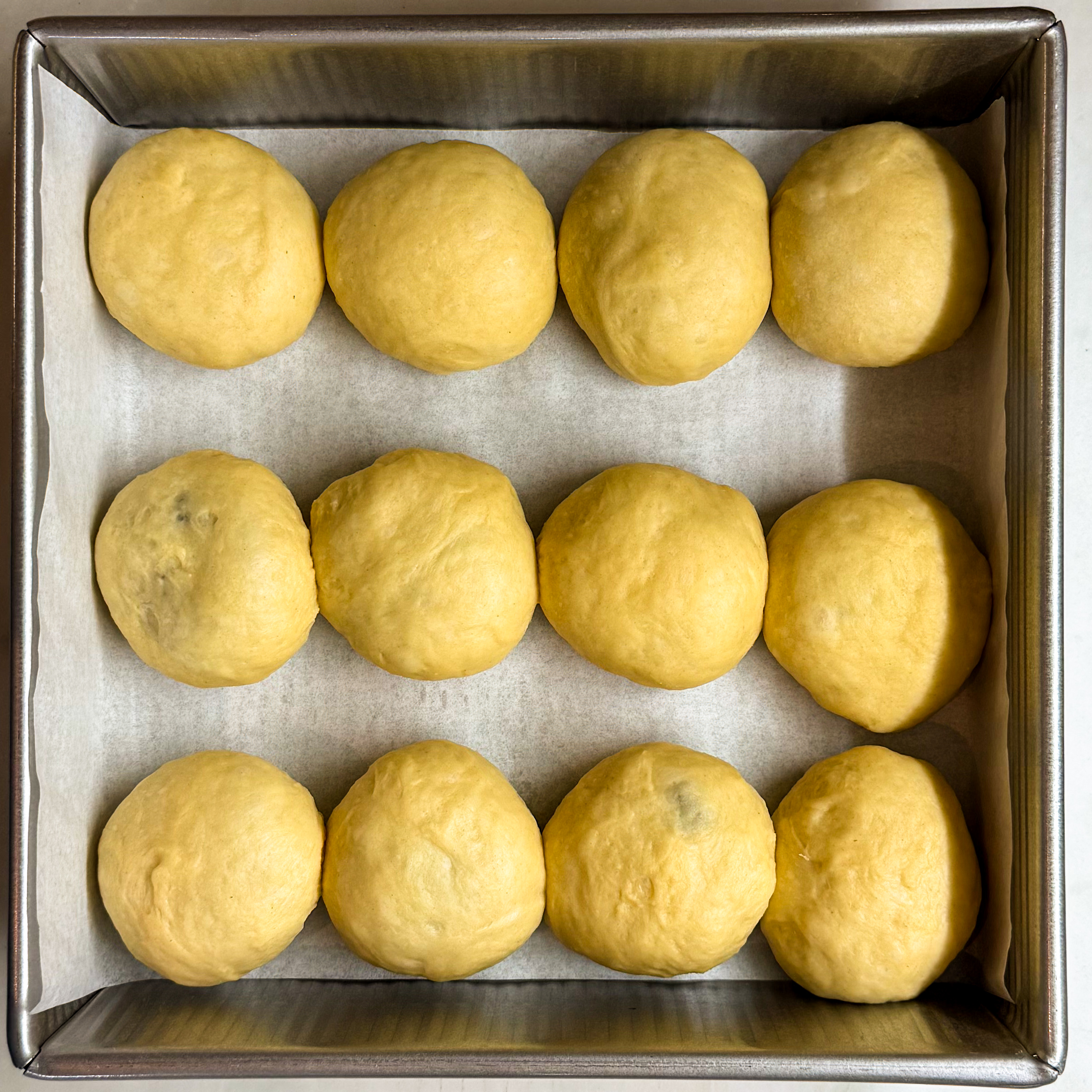 Overhead of shaped rolls in baking pan showing space gaps between the rolls.
