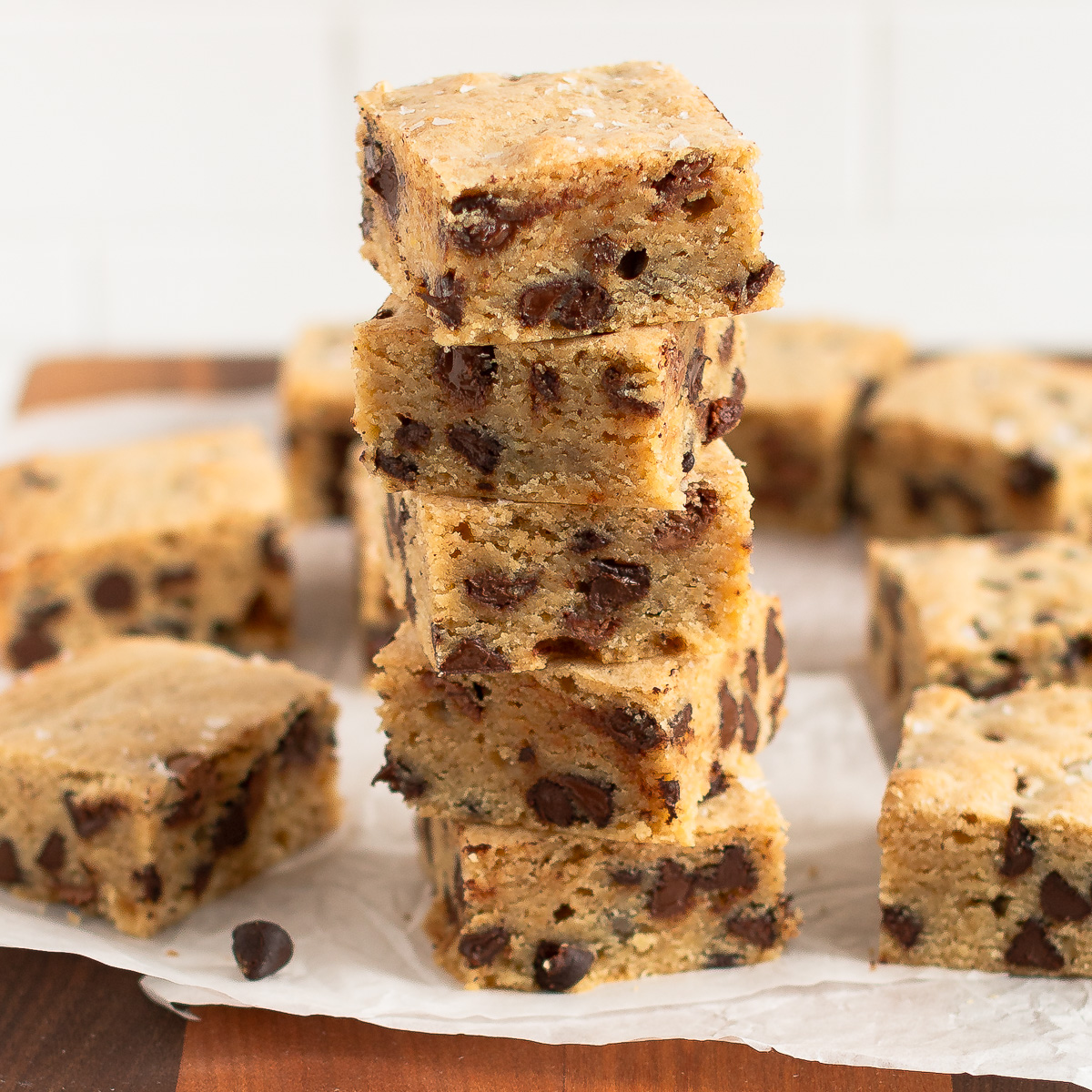 Five sourdough blondies stacked with more on the sides and background. 