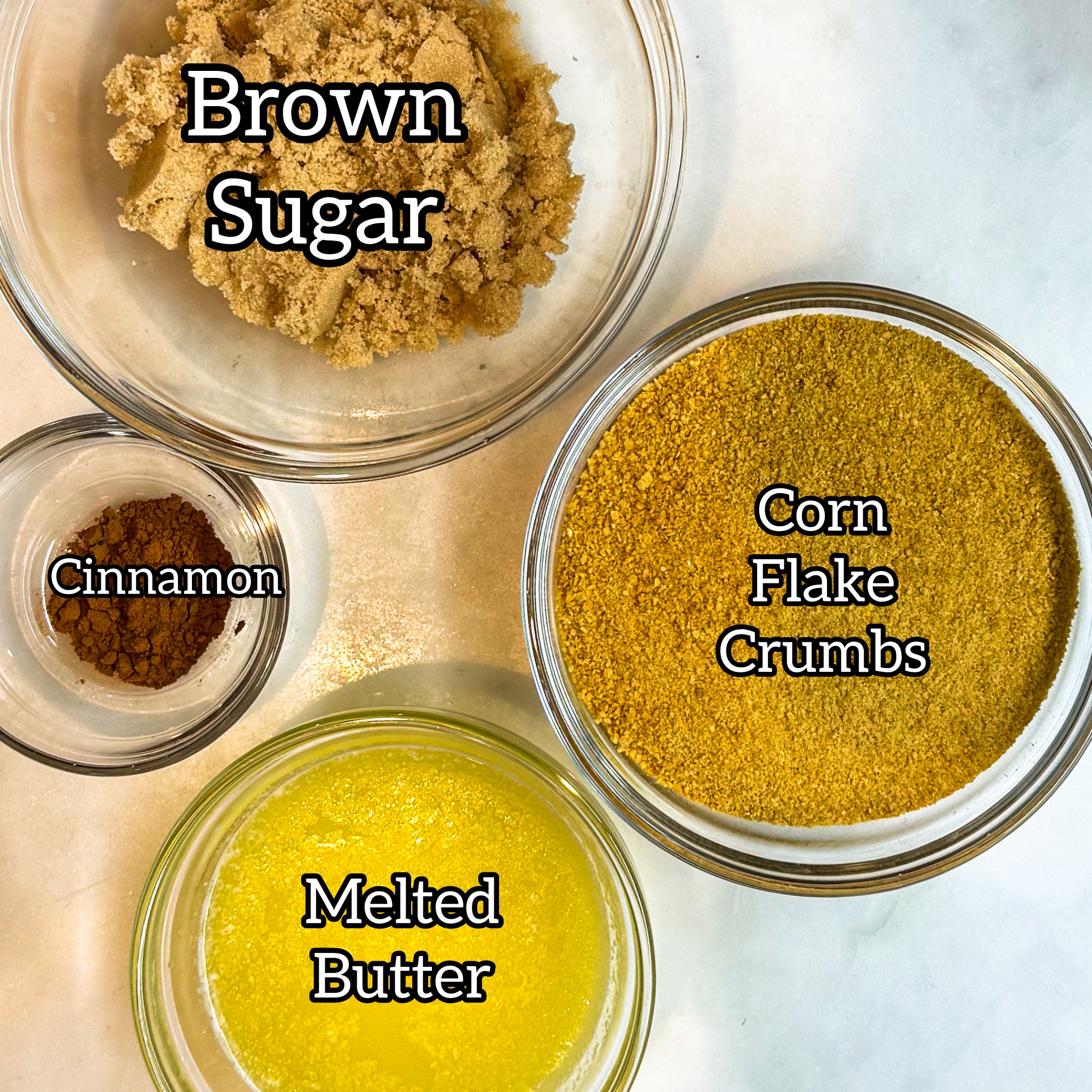 Overhead of the topping ingredients: brown sugar, Corn Flake crumbs, melted butter, and cinnamon. 